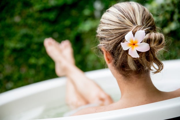 Lady sitting in a tub of water outdoors with her feet up on the edge