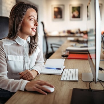 Women at desk with a computer smiling