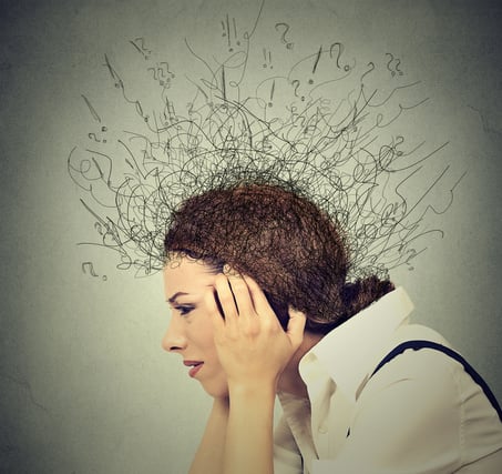 Woman with fingers on temples with overwhelming though symbols surrounding her head